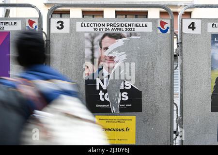 Un piéton passe sur un panneau d'affichage électoral une affiche de campagne officielle déchirée d'Emmanuel Macron. Affiches présidentielles sur leurs conseils électoraux. Illustration le 4 avril 2022 à Paris, France. Les électeurs français se rendront aux urnes le 10 avril 2022 pour le premier tour de l'élection présidentielle. Photo de Victor Joly/ABACAPRESS.COM Banque D'Images