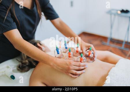 Ventouses placées sur le dos d'une patiente, par un massothérapeute. Centre médical de massage spa. Banque D'Images