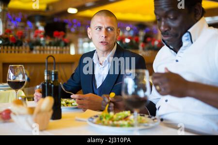 Deux beaux hommes en costume classique dînant au restaurant Banque D'Images