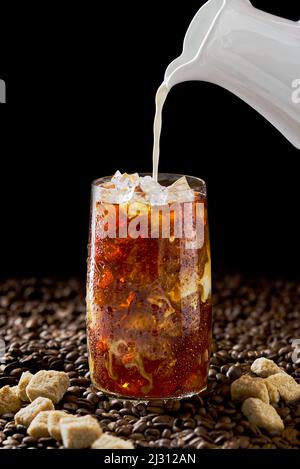 Café glacé. Délicieux café glacé au lait, boisson froide au verre avec glace sur fond de café sombre. Banque D'Images