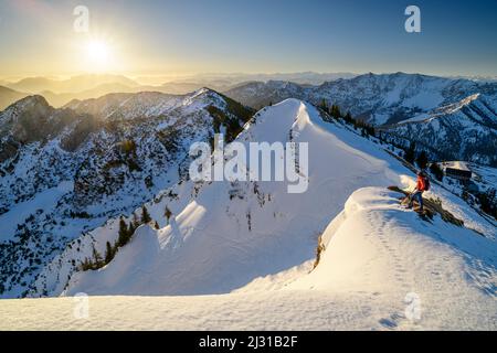 Femme de randonnée se dresse sur une crête enneigée et regarde les Alpes bavaroises et Chiemgau, Rotwand, Spitzing, Alpes bavaroises, haute-Bavière, Bavière, Allemagne Banque D'Images