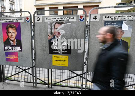 Un piéton passe sur un panneau d'affichage électoral une affiche de campagne officielle déchirée d'Emmanuel Macron. Affiches présidentielles sur leurs conseils électoraux. Illustration le 4 avril 2022 à Paris, France. Les électeurs français se rendront aux urnes le 10 avril 2022 pour le premier tour de l'élection présidentielle. Photo de Victor Joly/ABACAPRESS.COM Banque D'Images