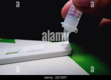 À la main, placer l'échantillon de sécrétions de gouttelettes dans le kit de test rapide d'antigène (ATK) du COV-2 du SRAS avec le tube d'extraction, protec infectieux du coronavirus Banque D'Images