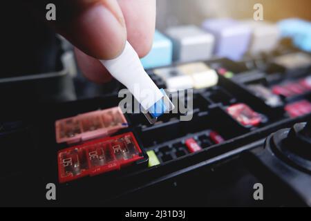 Le mécanicien remplace le fusible de rechange de la boîte à fusibles de la voiture par l'outil de fixation de fusible Banque D'Images