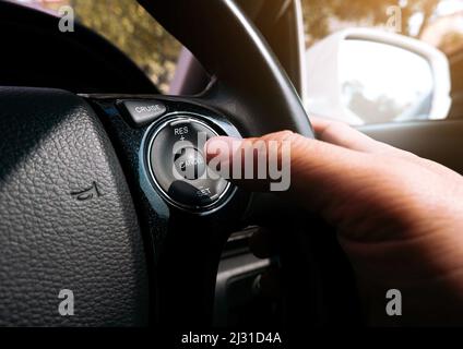 Le conducteur appuie avec sa main sur le bouton du régulateur de vitesse situé sur le volant de la voiture Banque D'Images