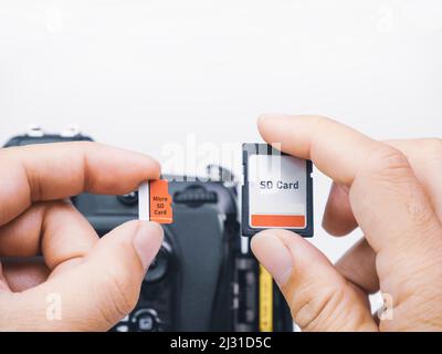 Les cartes mémoire micro SD et SD sont comparées pour une utilisation avec des appareils photo numériques reflex numériques entre les mains d'un photographe Banque D'Images