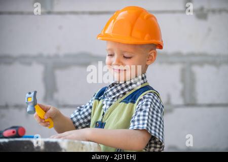 Portrait de petit constructeur en casques avec instruments pour la rénovation sur la construction. Garçon de créateur, enfant de menuisier avec ensemble d'outils de constructeur. Réparer la maison Banque D'Images