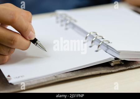 gros plan en tenant un stylo et en écrivant sur l'ordinateur portable. Banque D'Images