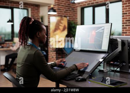 3D artistes numériques assis à un bureau d'ordinateur tout en travaillant sur le design environnemental. Responsable de l'équipe du département de production de l'agence de création développant une technologie de jeu professionnelle. Banque D'Images