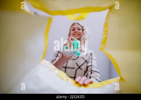 Image de l'intérieur du sac de recyclage jaune de femme jetant un plastique pour recycler. Banque D'Images