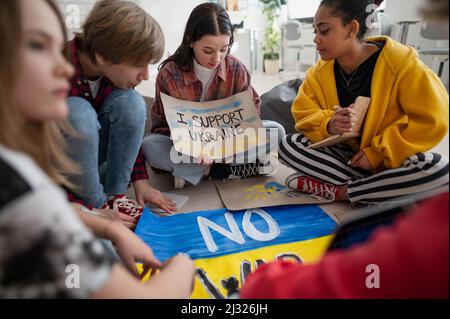 Les adolescents assis au cercle dans la salle de classe avec des affiches pour soutenir l'Ukraine, pas de concept de guerre. Banque D'Images