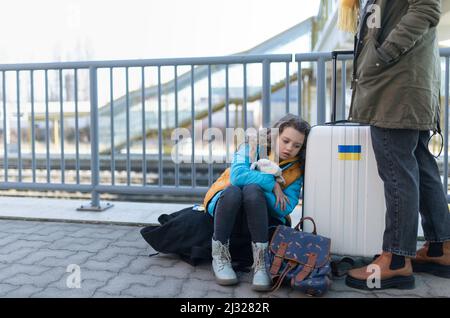 Tristes immigrants ukrainiens avec des bagages à la gare, concept de guerre ukrainien. Banque D'Images