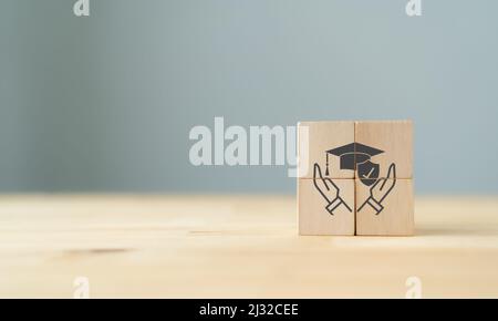 Concept d'assurance pour l'éducation. Protection et étude, signe de sécurité de l'éducation. Les cubes en bois avec protection et sécurité des symboles de l'éducation Banque D'Images