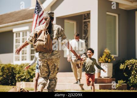 Une femme soldat se réunirait avec sa famille après avoir servi dans l'armée. Une militaire américaine reçoit un accueil chaleureux de son mari et de ses enfants. Militaire Banque D'Images