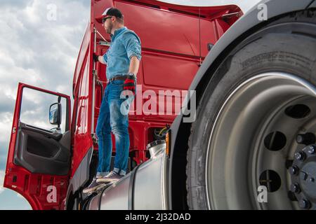 Chauffeur caucasien professionnel dans son 30s debout sur un semi-tracteur camion. Industrie du transport lourd. Banque D'Images