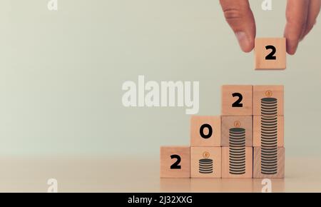 Croissance du concept d'investissement en crypto-fréquence en 2022. Gros plan à la main en organisant des cubes en bois empilés '2022' sur la croissance de l'empilage de bitcoin. Blanc Banque D'Images