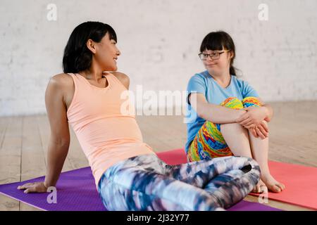 Jeune femme avec le syndrome de Down ayant un cours de yoga de groupe à l'intérieur Banque D'Images