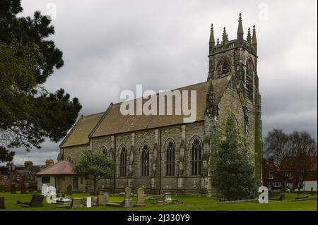 Église Saint-Nicolas avec vue sur les pierres tombales et flanquée de pelouses et d'arbres dans un ciel nuageux sur un morninbg printanier à Beverley, Yorkshire, Royaume-Uni. Banque D'Images