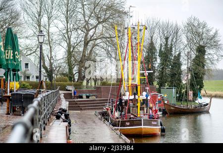 Hooksiel, Allemagne. 05th avril 2022. Un coupe-pêche et une réplique d'un bateau viking sont amarrés dans le vieux port de la ville côtière par temps pluvieux. Credit: Hauke-Christian Dittrich/dpa/Alay Live News Banque D'Images