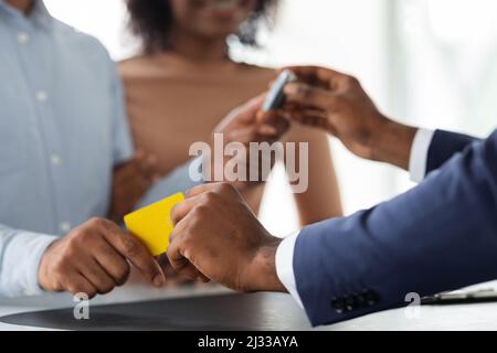 Black Manager prenant la carte de crédit et donnant des clés de voiture à un jeune couple Banque D'Images