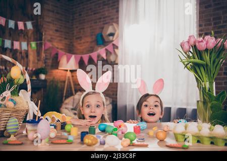 Portrait de beaux frères et sœurs gaies dessinant des œufs se cachant derrière le bureau table de bureau ayant amusant maison personnalisée à l'intérieur Banque D'Images