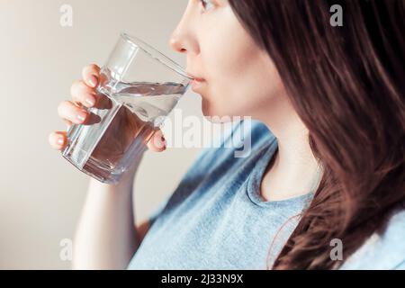 Une femme boit de l'eau propre. Journée mondiale de l'eau. Concept de soins de santé. Régime et détox, augmenter le métabolisme. La main tient un verre d'eau potable. Banque D'Images