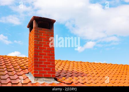 Cheminée en briques sur le toit et ciel partiellement nuageux sur le fond. Arrière-plan de l'architecture traditionnelle. Banque D'Images