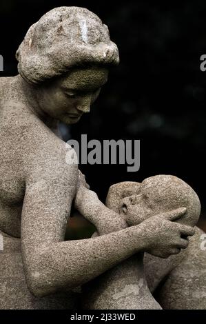 Une mère soutient doucement la tête de son bébé alors qu'elle se prépare à l'allaiter, dans ce détail de « l'abondance » du sculpteur britannique Francis Derwent Wood (1871-1926). La statue, avec deux autres, forme la pièce maîtresse sculpturale de la roseraie de Hampton court, le palais royal historique fondé au 16e siècle à côté de la Tamise dans le quartier londonien de Richmond-upon-Thames, en Angleterre. Banque D'Images