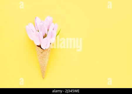 Tulipes roses dans un cône de glace gaufré sur fond jaune. Fête des mères, Saint Valentin, Bachelorette, concept d'été. Copier l'espace pour le texte Banque D'Images