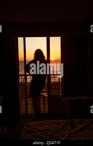 Silhouette d'une personne, d'un homme, debout sur un balcon extérieur donnant sur le lever du soleil au-dessus de l'océan Atlantique. La personne est rétro-éclairée tôt le matin Banque D'Images