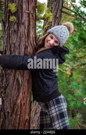 Portrait d'une fille souriante embrassant un pin. Banque D'Images