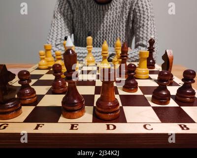 Homme pensant et analysant le jeu d'échecs sur le plateau d'échecs - concept stratégique. Banque D'Images