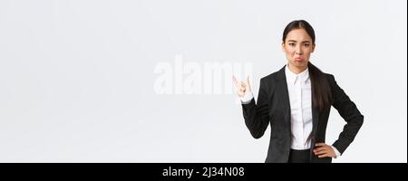 En colère, une vendeuse déçue en costume noir se plaignant de petites tailles misérable, montrant quelque chose de minuscule et de poudant déplaisés, se tenant gêné Banque D'Images