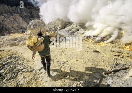 Fourreaux transportant des paniers avec du soufre à l'intérieur du cratère du volcan Ijen, île de Java, Indonésie Banque D'Images