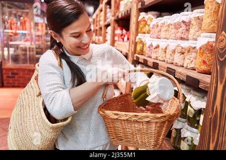Un jeune client met le produit régional dans le panier d'achat du supermarché tout en faisant du shopping Banque D'Images