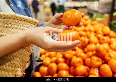 Client au stand de fruits dans le supermarché lors de l'achat de mandarines comme marchandises d'importation Banque D'Images