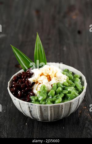 Desserts malaisiens appelés Cendol. Le Cendol est fabriqué à partir de cubes de glace écrasés, de haricots rouges. Également populaire à Singapour. Sur une table en bois Banque D'Images