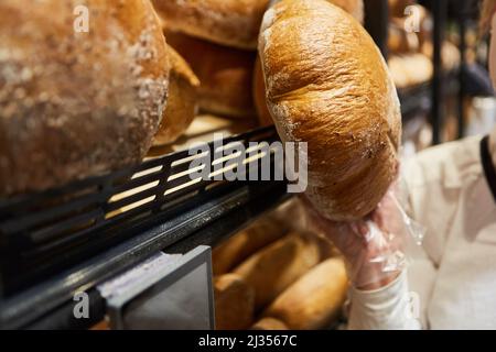 Main prend un pain de pain de l'étagère dans la boulangerie ou boulangerie magasin dans le supermarché Banque D'Images
