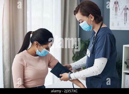 Je vais juste mettre ça autour de votre bras. Prise de vue d'une jeune femme médecin vérifiant la tension artérielle d'un patient dans un bureau. Banque D'Images