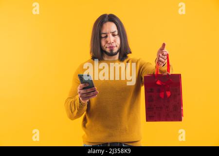 Déçu un homme européen en colère tenant un cadeau qu'il a acheté via le shopping en ligne. Échec du concept d'achat en ligne. Photo de haute qualité Banque D'Images