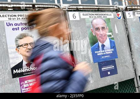 Paris, France, le 5 avril 2022, Un piéton passe un poster officiel de campagne du candidat d'extrême gauche Jean-Luc Melenson et celui du candidat d'extrême droite Eric Zemmour, sur un panneau d'affichage électoral (panneau). Affiches présidentielles sur leurs conseils électoraux. Illustration le 5 avril 2022 à Paris, France. Les électeurs français se dirigent vers les urnes pour voter le 10 avril 2022 pour le premier tour de l'élection présidentielle, pour élire leur nouveau président de la République. Photo de Victor Joly/ABACAPRESS.COM Banque D'Images