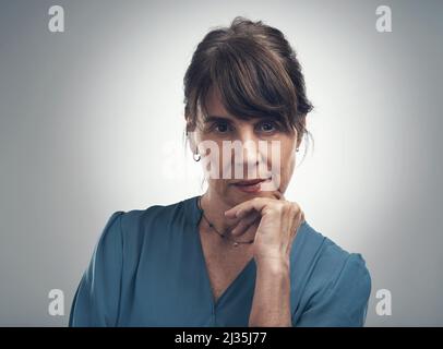 Vous êtes à la recherche d'un véritable Go-getter. Portrait studio d'une femme âgée posant avec sa main sur son menton sur un fond gris. Banque D'Images