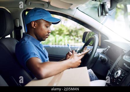 Signé, scellé et livré. Photo d'un jeune poste travaillant assis dans sa voiture pendant une livraison. Banque D'Images