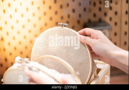 Femme main choisir le cadre de broderie de bois avec le motif de couture dans un processus de handiwork. Le week-end, profitez de votre temps libre. Banque D'Images