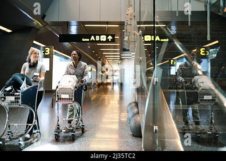 Nos sacs sont emballés et étaient prêts à l'emploi. Prise de vue en longueur de deux jeunes femmes attrayantes qui marchent à travers un aéroport. Banque D'Images