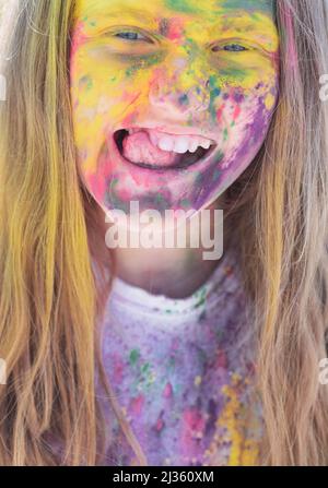 Passe-temps insouciant. Une vie heureuse à l'adolescence. Camp de vacances. Fille émotionnelle avec humeur heureuse avec des couleurs sèches colorées. Holos colorés sur le visage peint Banque D'Images