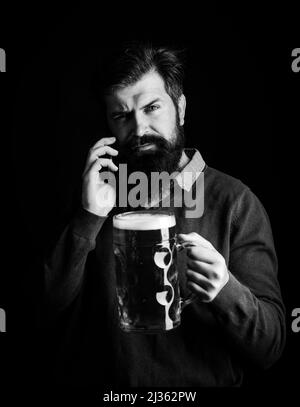 Le concept du festival de la fête de la bière. Portrait d'un jeune homme charmant qui goûtant une bière à la pression. Sympa et drôle, l'hipster à barbe tient le métier Banque D'Images