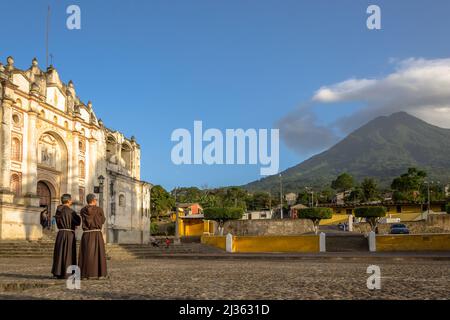 Deux prêtres catholiques franciscains regardant le volcan Agua au coucher du soleil à l'église San Juan del Obispo, juste avant d'aller à la messe. Banque D'Images