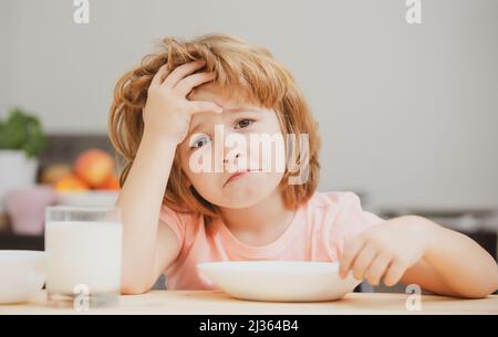 Pas faim. Enfant refusant de manger. L'enfant n'a pas d'appétit. Le petit enfant contrarié refuse de manger des céréales biologiques avec du lait. Nutrition de l'enfant. Banque D'Images