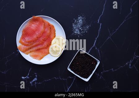 Directement au-dessus d'une dose de saumon fumé avec des épices sur fond noir Banque D'Images